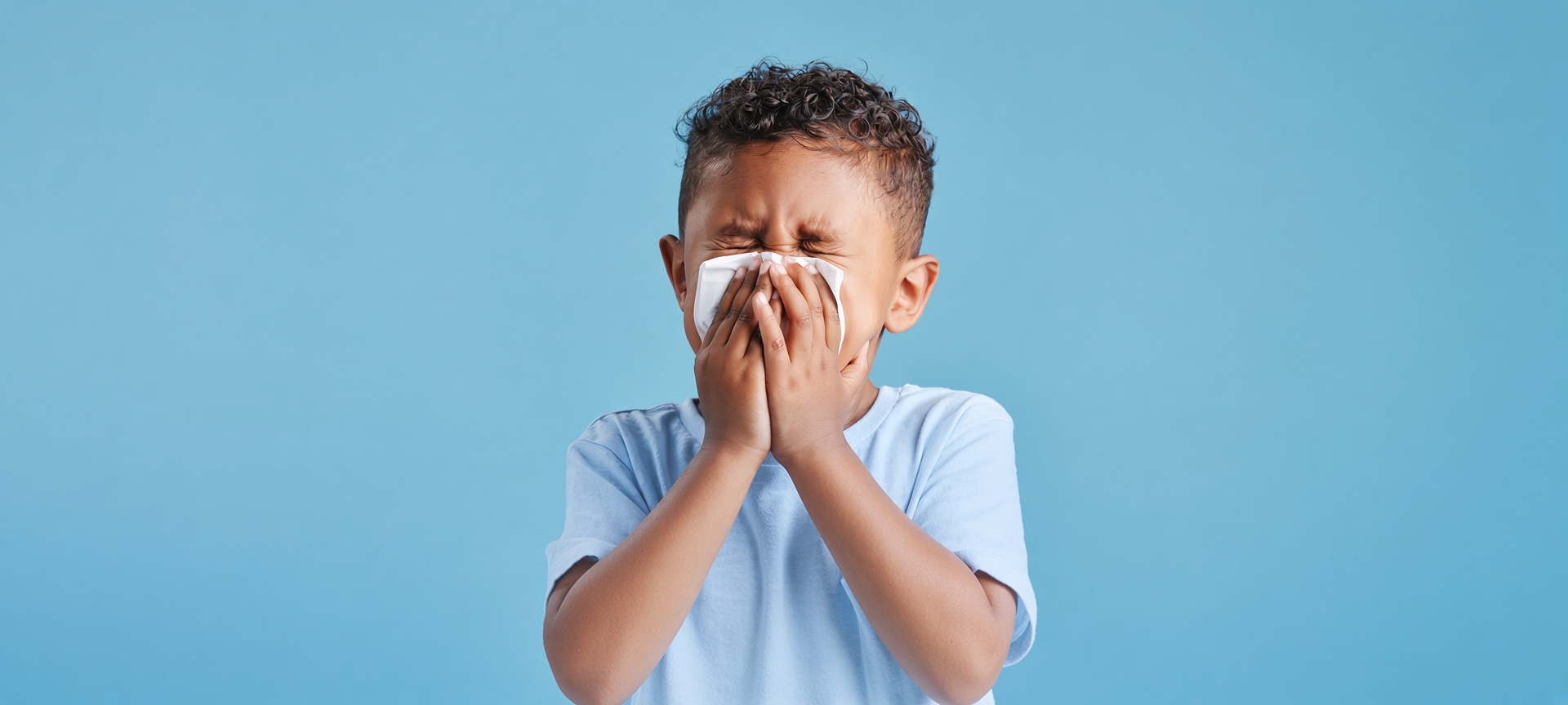 Child sneezing into a tissue due to poor indoor air quality