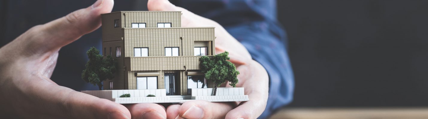 Hands holding a small model house